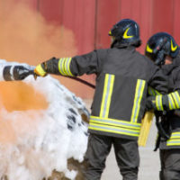 firefighters in action with foam to put out the fire of the car