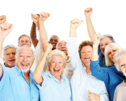 Group of happy senior citizens with their hands raised over white